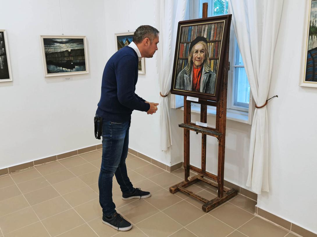 Önarckép 80 évesen. Idős nő portréja könyvespolc előtt. Fekete sapkát, piros sálat és szürke kabátot visel., Corini Margit festőművész születésének 125., halálának 40. évfordulójára rendezett emlékkiállítás, Vidovszky Béla Városi Képtár, Gyomaendrőd Önarckép 80 évesen. Idős nő portréja könyvespolc előtt. Fekete sapkát, piros sálat és szürke kabátot visel., Corini Margit festőművész születésének 125., halálának 40. évfordulójára rendezett emlékkiállítás, Vidovszky Béla Városi Képtár, Gyomaendrőd