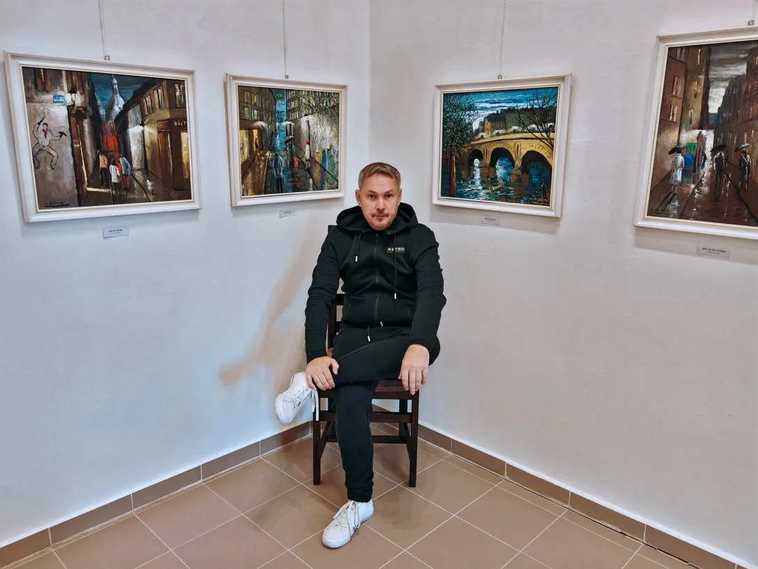 Középen "Egy magányos fiú ül Corini Margit festményei között, aki művészetkedvelő és művészeti elemző." Jobb oldalán látható a "Tavaszi este" című festmény, amely egy szűk utcán siető emberi alakokat ábrázol. A kép központjában egy esernyőt tartó férfi vezeti a kislányát, mellettük egy nő halad, kezében összecsukott ernyővel. Bal oldalán található a "Híd a Szajnán" című festmény, amelyben egy piros ruhás nő ül, aki csónakban evez a híd alatt, míg a parton egy horgászó férfi figyeli a vizet.